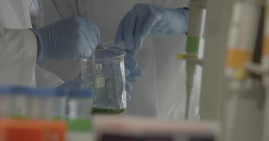 A person pours a vial of liquid into a glass container