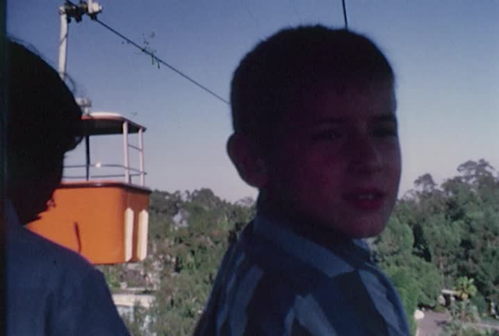 Old footage of children on a gondola ride as other gondola cars pass by