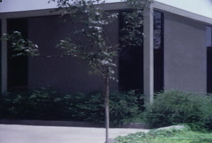 Large brown building with green bushes