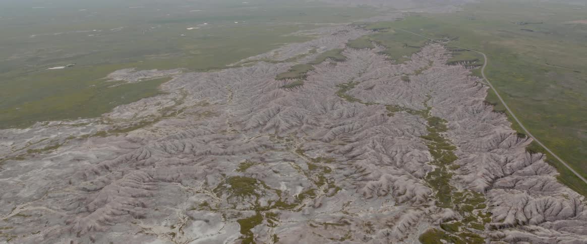 An enormous green grassy landscape has a long chains of hills transecting it
