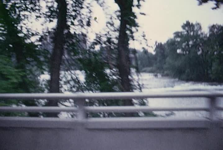 A river and building seen through the window of a car as it passes