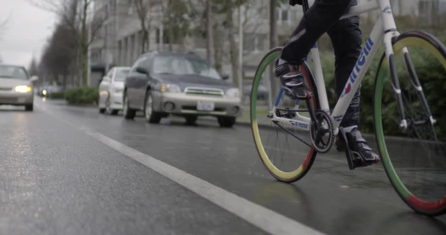 A person rides their bike down a street in the rain