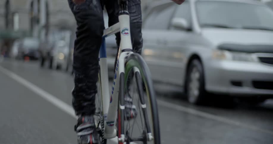 A bicyclist pedals down a city street during a storm