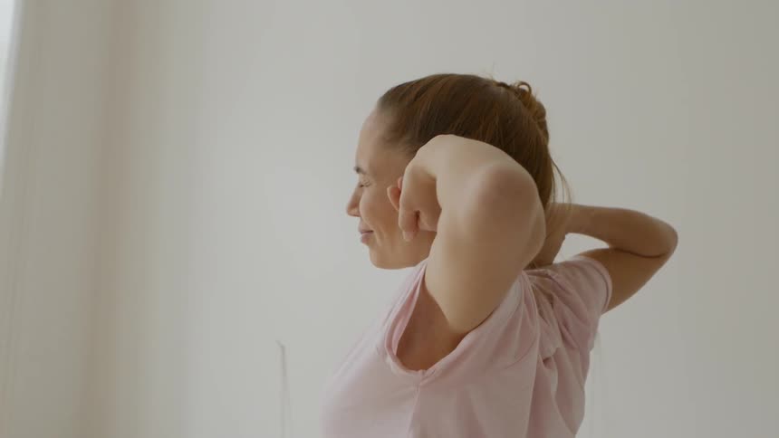 A woman is rubbing her face as she gets up