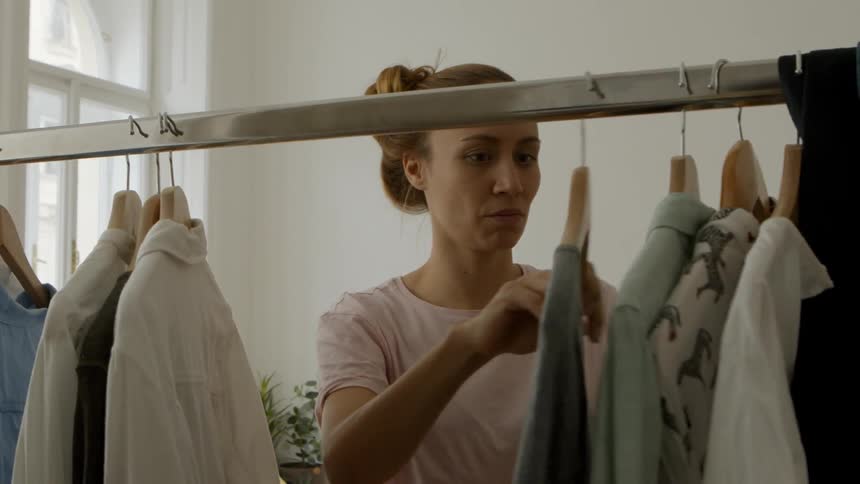 A woman looking through shirts on a clothing rack