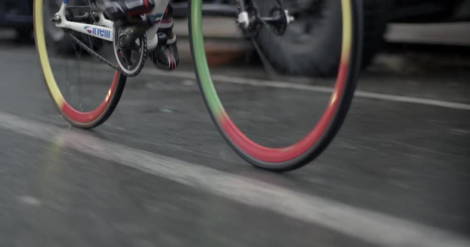 Multi colored bicycle wheels move as a bike is pedaled on a city street