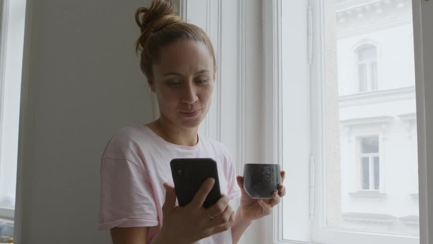 A woman looks out the window while answering phone