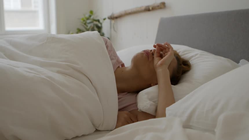 A woman wakes up in bed