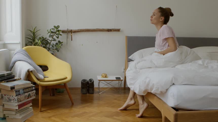 A woman climbing out of bed