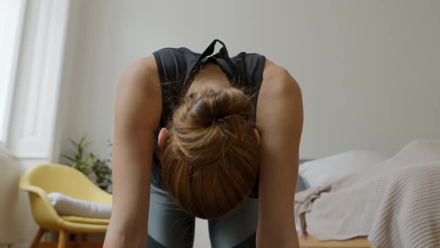 A woman does yoga in her bedroom