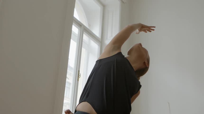 A woman stretches her arms up and down while doing yoga