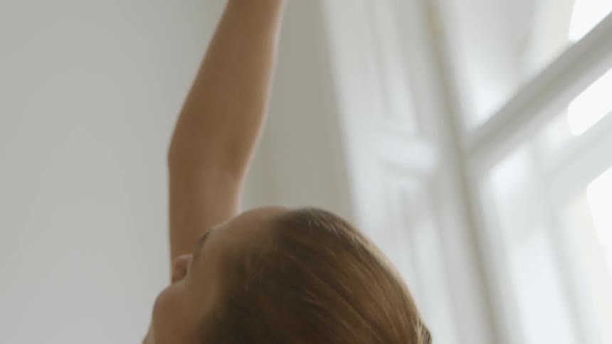 A woman stretches inside a room