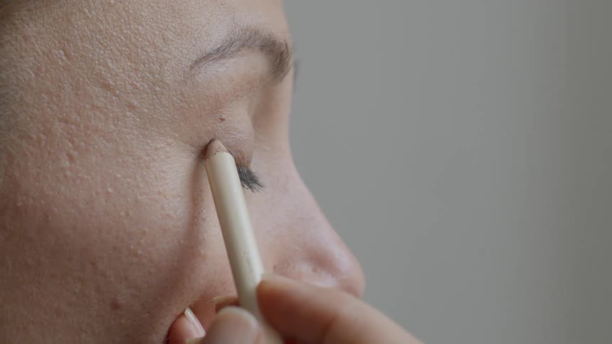 A woman puts on eyeliner