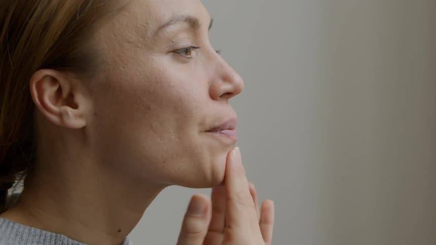 Woman rubs lotion onto her face
