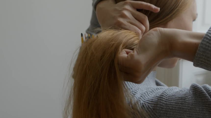 A woman runs a comb through her long red hair