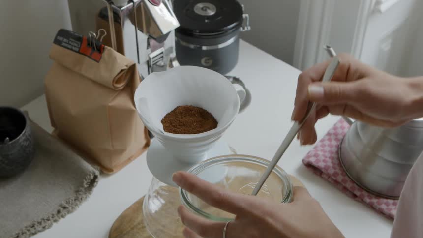 A woman puts coffee grounds in to her coffee maker