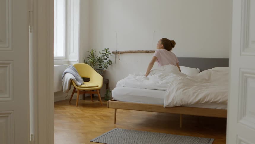 A woman wakes up and stretches in bed