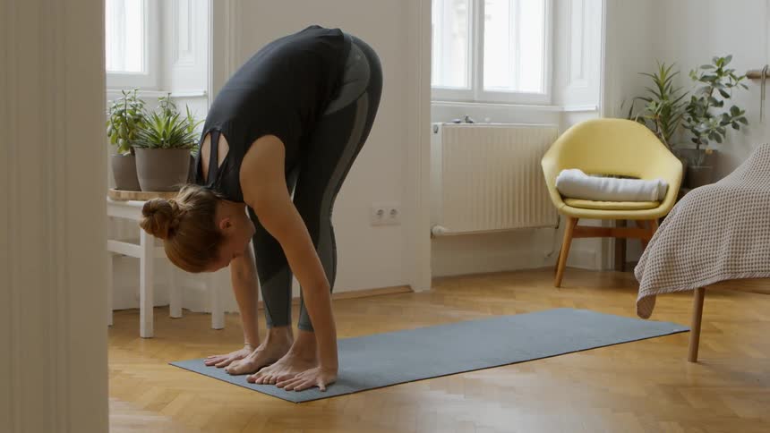 Young woman doing yoga stretches in living room