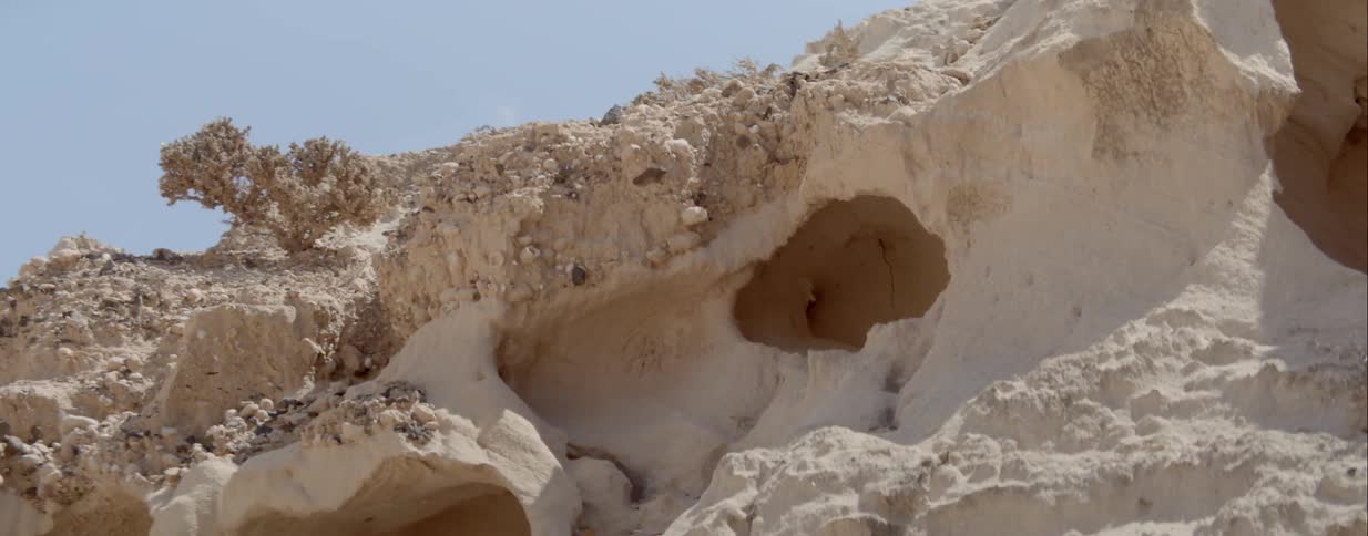 White walled water eroded cave under a clear blue sky