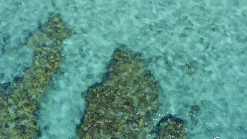 A coral reef with blue waters rippling in the sun