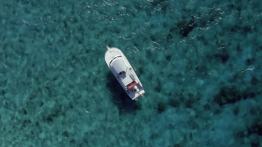 A boat is anchored in clear turquoise tropical waters