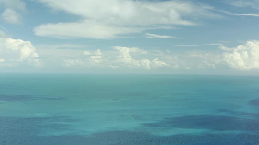Clouds are scattered across a light blue ocean