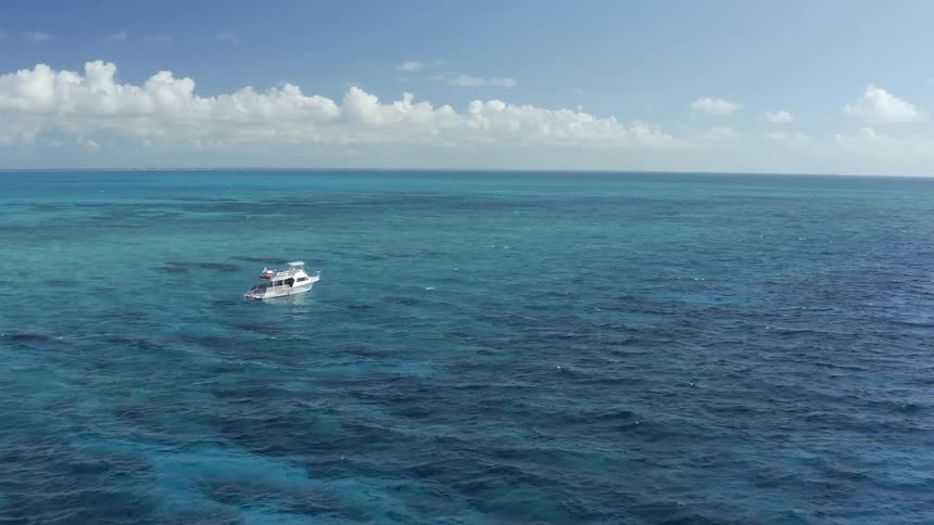A boat bobs on the waves in clear blue water on a sunny day