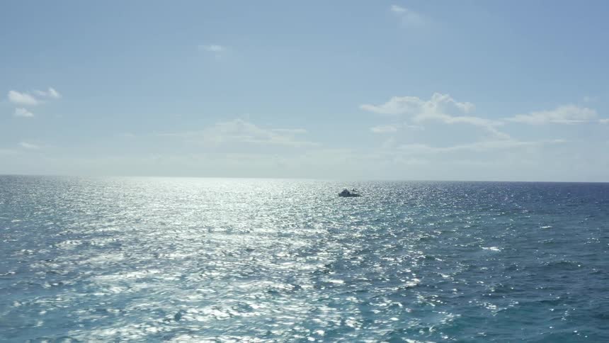 A boat bobs alone in the blue ocean on a sunny day