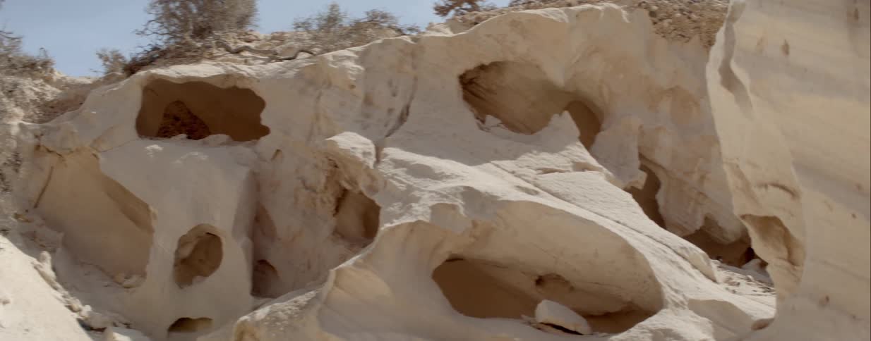 Caves and holes formed in white smooth rock hillside by erosion