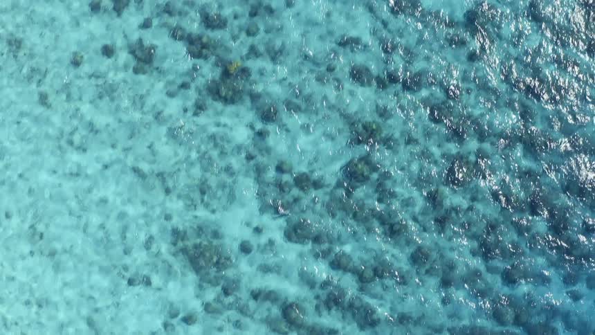 Surface of translucent blue water ripples over seabed