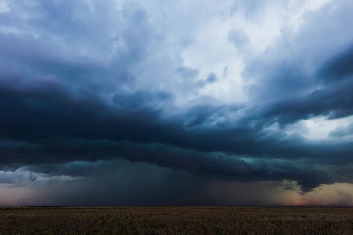 A thunder storm with lightning and rain moves over a crop field