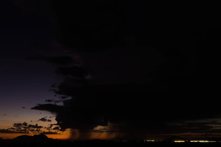 A storm with numerous flashes of lightning passes overhead as daylight fades