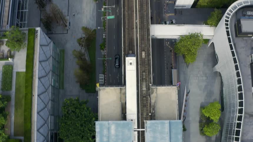 Birds eye view of train leaving station on city downtown at day