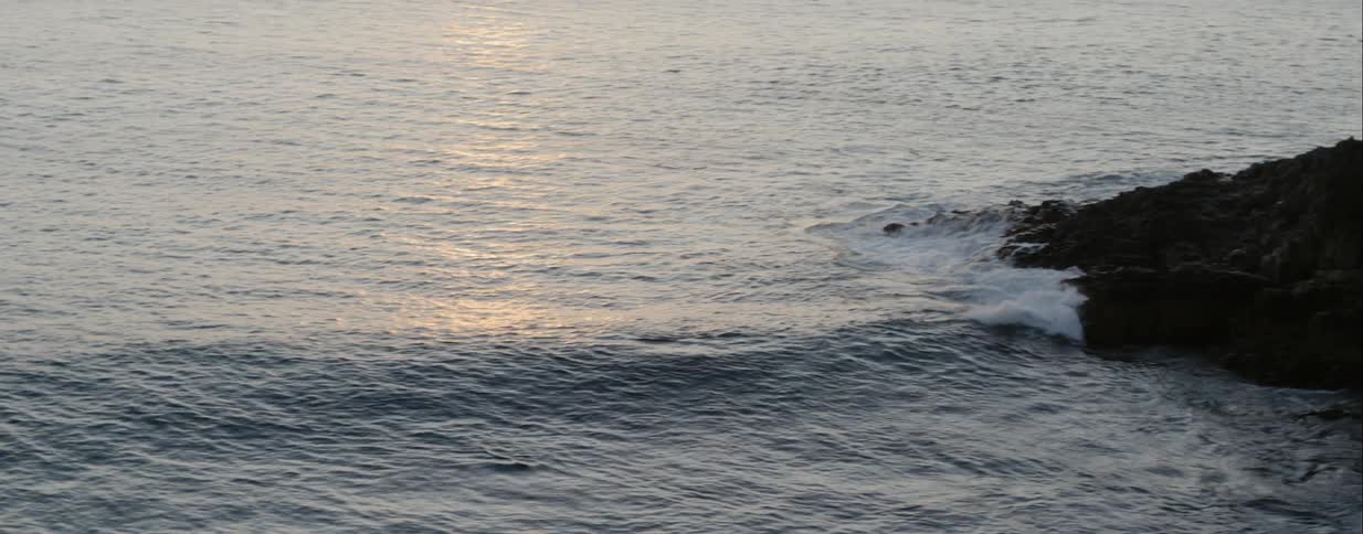 A wave rolls in and crashes on rocks
