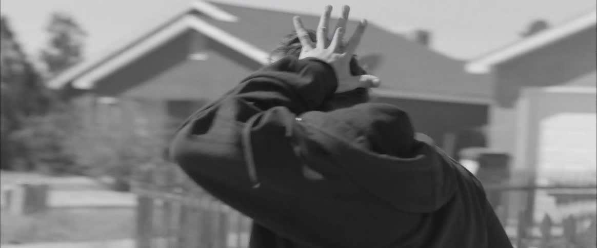 A man rubs the back of his head while walking on a neighborhood street