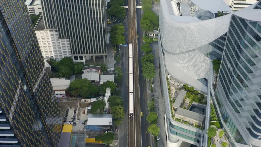A train drives down a rail surrounded by skyscrapers in a large city