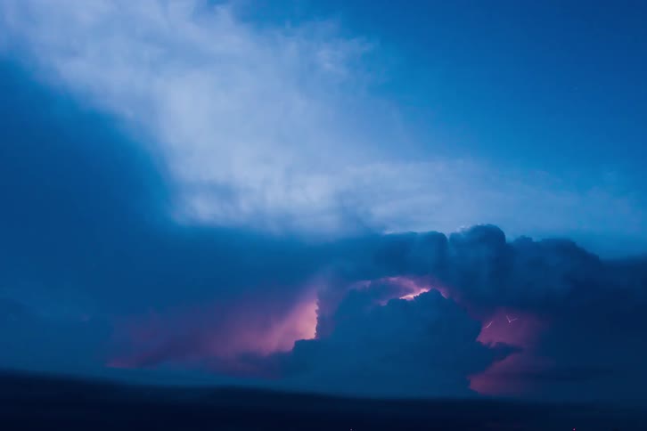 Lightning lights up clouds as they flow across the sky