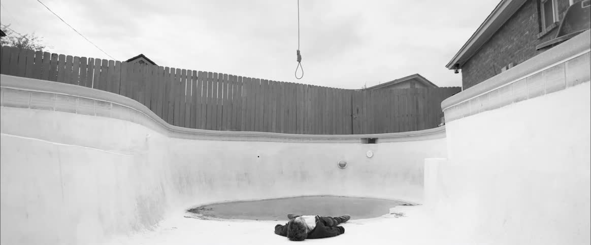 A person lies on the bottom of an empty swimming pool