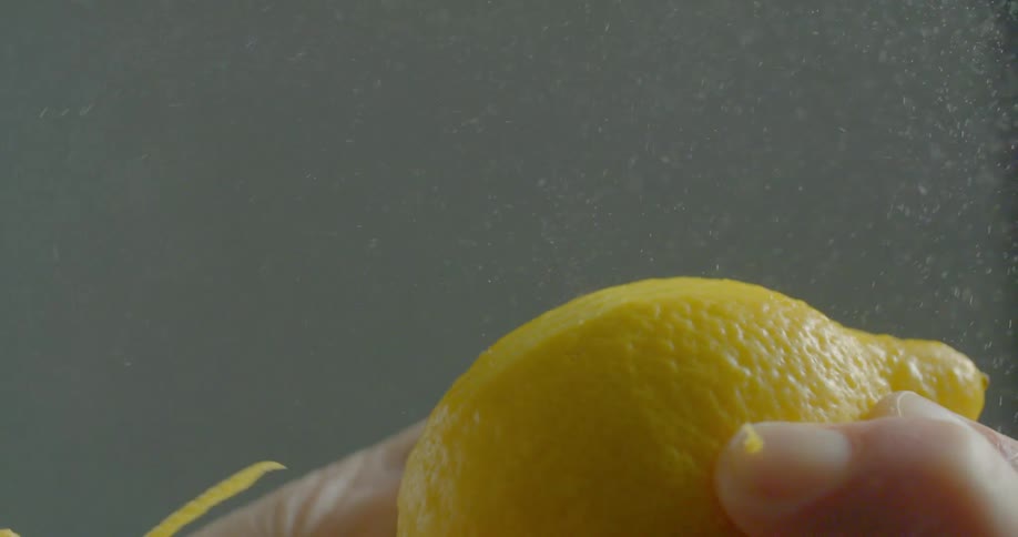 Man peels lemon zest with peeler