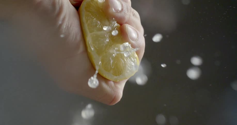 A person squeezes a lemon so juice comes out of it