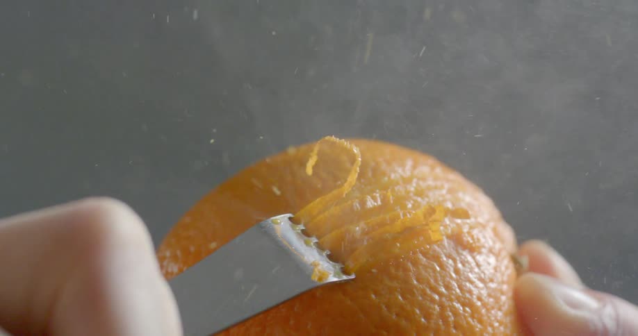 Close up of orange zest being grated with a zester