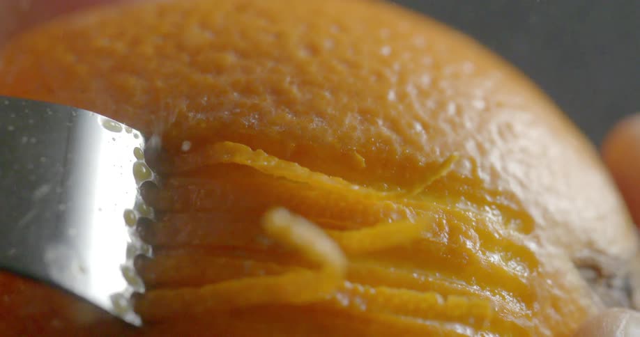 Juice splashes as someone scrapes an orange