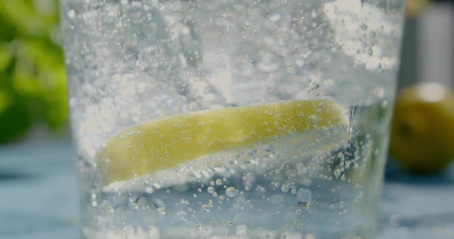 Slice of lime floating on carbonated water inside a glass