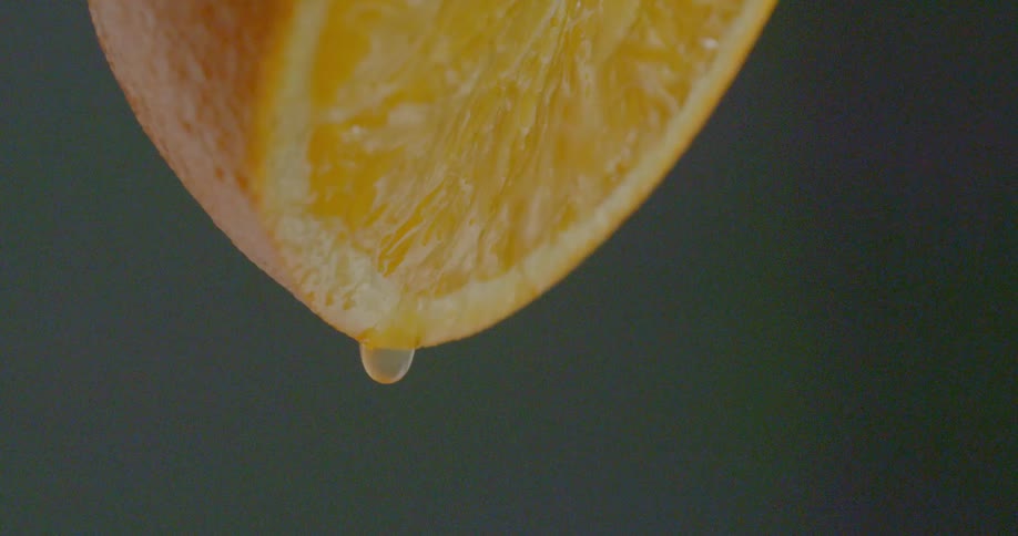An orange half is dripping juice slowly