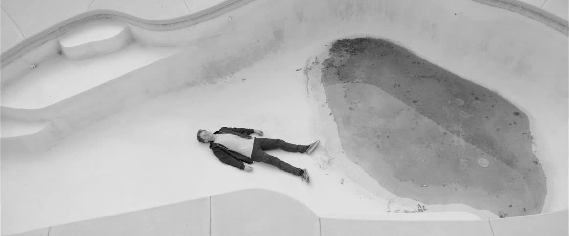 A person lays down at the floor of a dirty empty pool