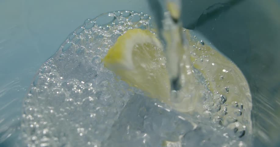 A drink is being poured over ice and a lemon slice