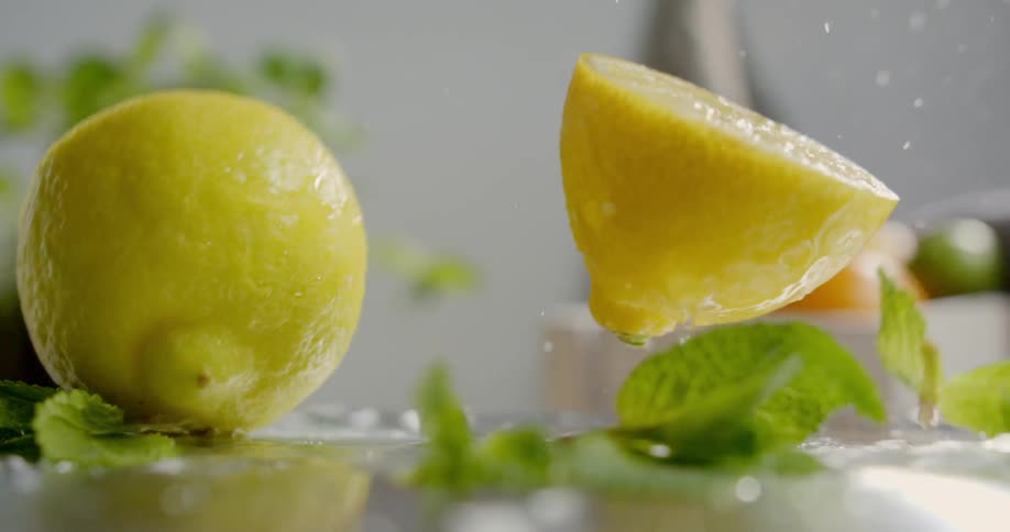 Two halves of a lemon drop onto table