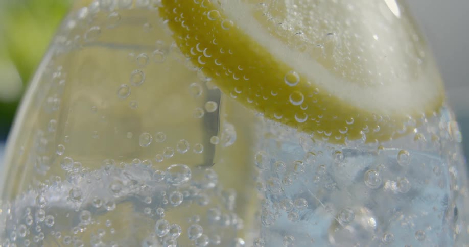 Bubbles rise in a drink with a lemon slice in it