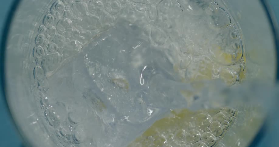 Water is being poured in to a glass with ice and lemon