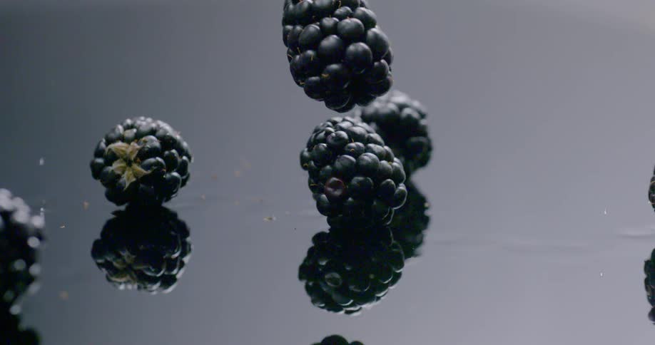 Blackberries fall onto a glass surface